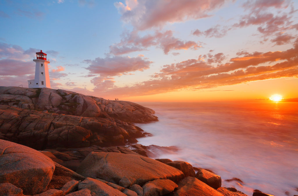 Beautiful Peggy Cove Light House with Sunset, Nova Scotia, Canada. Photo shows tourists watching sunset.