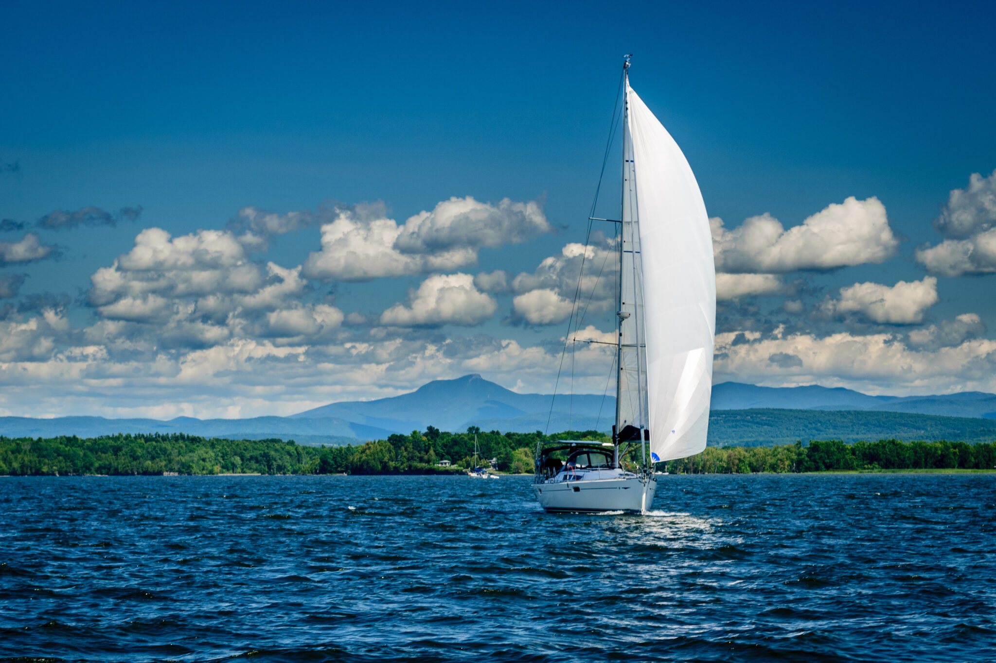 Sailboat on Lake Champlain with Vermont mountains in the distance