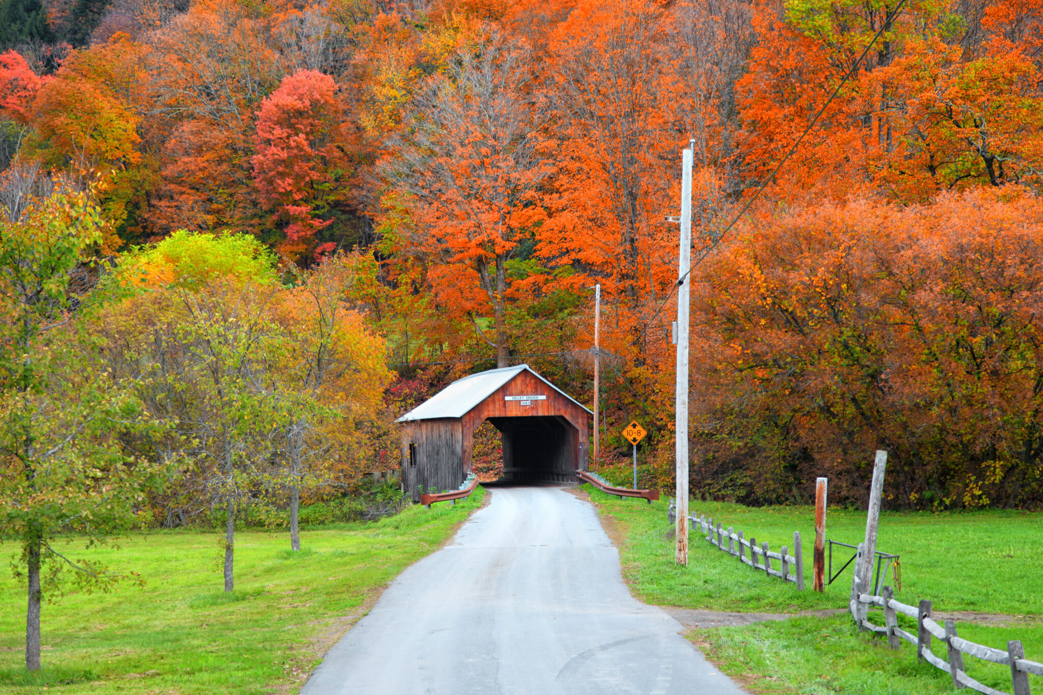 Covered bridge along a country road surrounded by Vermont fall foliage